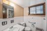 Full bathroom with a tile shower, vanity, radiator heating unit, tile walls, and a wainscoted wall