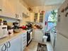 Kitchen with white appliances, light countertops, light tile patterned floors, glass insert cabinets, and white cabinetry