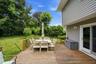 Spacious wood-finish deck bordered by a wooden railing overlooking a lush green lawn and mature trees