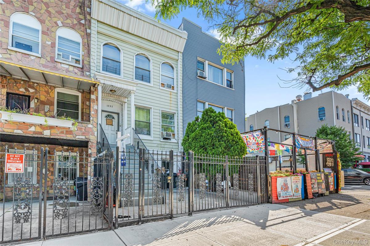 Light-colored facade with prominent entry staircase and wrought iron fencing