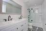 Bathroom featuring double vanity, combined bath / shower with glass door, and recessed lighting