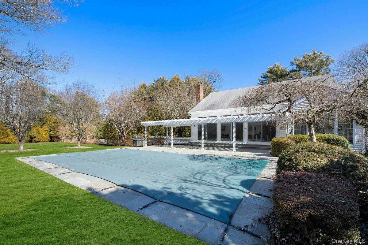 Side overview of entertaining and recreation area featuring patio, pool, tennis, park like backyard