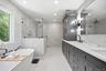 Spacious bathroom featuring a Fleurco Opus Collection freestanding soaking tub, a large glass-enclosed shower, dual vanity with undermount sinks, cust