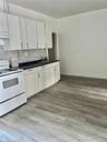Kitchen featuring white electric stove, white cabinetry, backsplash, and light hardwood / wood-style flooring
