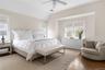 Bedroom with vaulted ceiling, wood finished floors, visible vents, and multiple windows