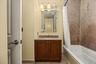 Bathroom featuring a wood vanity with a light-toned countertop, an integrated sink, and a wall-mounted mirror with overhead lighting