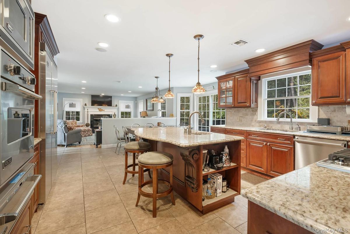 Kitchen with a breakfast bar, open shelves, open floor plan, light stone countertops, and a warming drawer