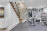 Finished lower level featuring a full staircase with wood treads and decorative iron balusters, stone accent walls, recessed lighting with lots of sto