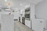 Bonus: Contemporary kitchen space featuring a waterfall island with veined quartz, recessed lighting, and a gold-tone linear chandelier