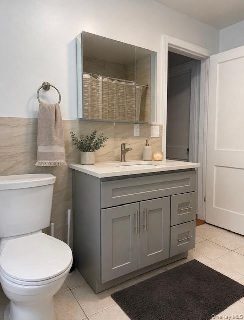 Bathroom featuring a gray shaker-style vanity with white countertop, integrated sink, and brushed nickel faucet