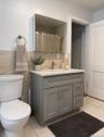 Bathroom featuring a gray shaker-style vanity with white countertop, integrated sink, and brushed nickel faucet