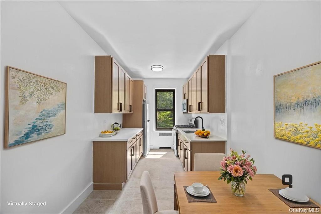 Sleek kitchen featuring wood-finish cabinetry, light-toned countertops, and a stainless steel refrigerator