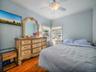 Bedroom with crown molding, dark wood-type flooring, a ceiling fan, and radiator