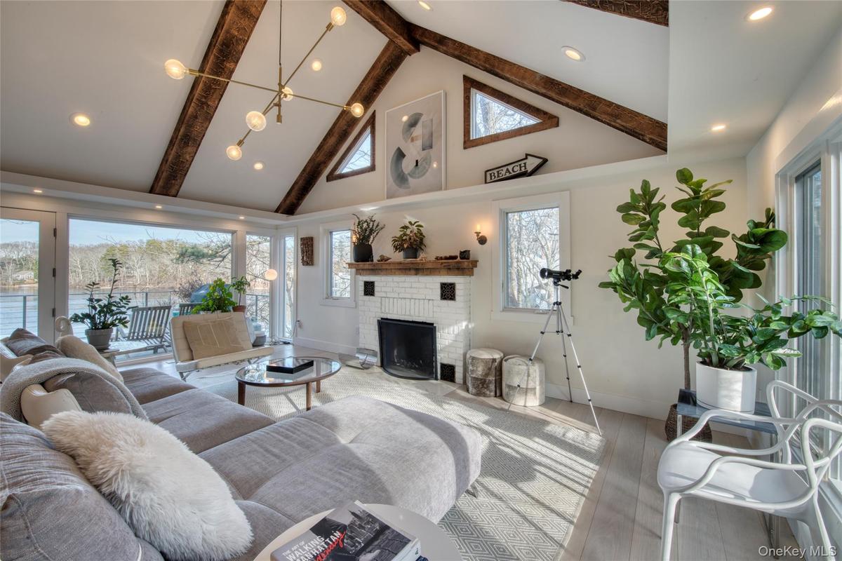 Living room with high vaulted ceiling, beamed ceiling, a fireplace, and wood finished floors