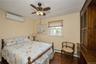 Bedroom with dark wood-style floors, a wall mounted AC, crown molding, a ceiling fan, and baseboard heating