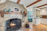 Detailed view of beamed ceiling, wood finished floors, a fireplace, and tasteful backsplash