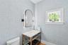 Half bathroom with toilet and wallpapered walls
