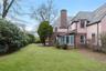 Back of property featuring a lawn, a chimney, brick siding, and stucco siding