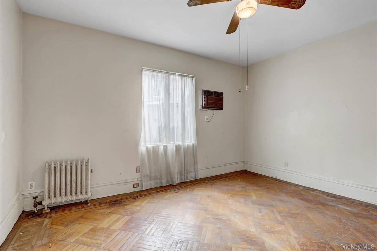 Unfurnished room with radiator, ceiling fan, and a wall mounted AC