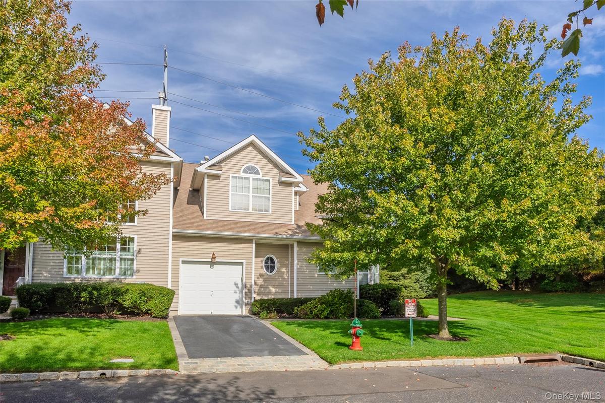 View of front of home featuring a front lawn, driveway, a shingled roof, a garage, and a chimney