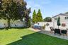 Expansive backyard featuring a manicured lawn, a large shade tree, and a white privacy fence