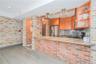 Kitchen with brick wall, light stone counters, light wood-style floors, stainless steel appliances, and a peninsula