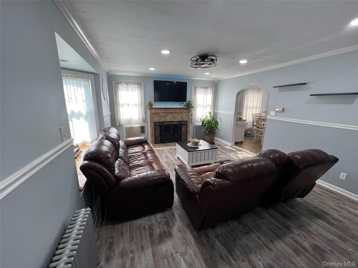 Bright, open living room anchored by a fireplace with stone surround and wood mantel, centered beneath a wall-mounted flat-screen television