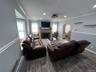 Bright, open living room anchored by a fireplace with stone surround and wood mantel, centered beneath a wall-mounted flat-screen television