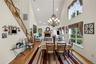 Dining space with a high ceiling, a glass covered fireplace, recessed lighting, light wood-style flooring, and stairway