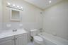 Full bath with tile walls, bathtub / shower combination, vanity, light tile patterned floors, and a wainscoted wall
