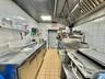 Kitchen featuring stainless steel counters, open shelves, and tile walls