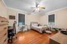 Bedroom with dark wood finished floors, a ceiling fan, a desk, and cooling unit