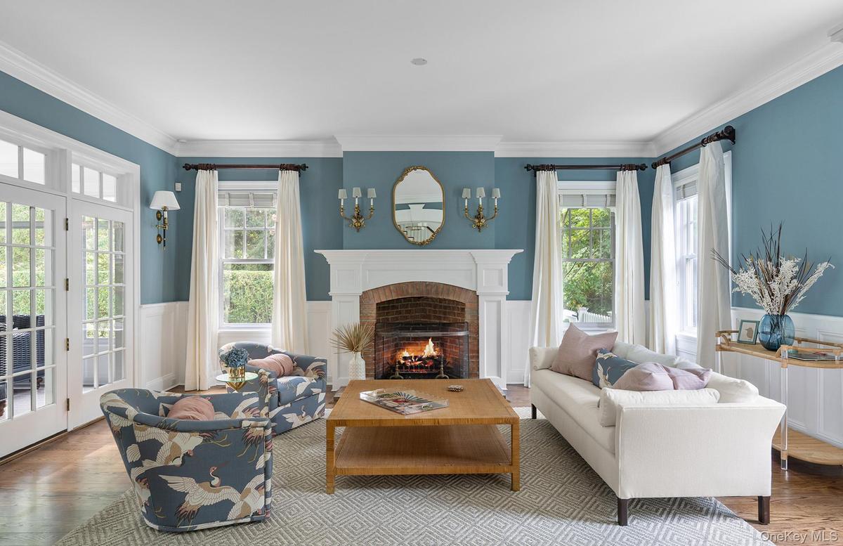 Living area featuring a healthy amount of sunlight, a wainscoted wall, wood finished floors, and a fireplace