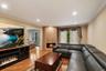 Living area featuring a corner fireplace with a stone surround, hardwood flooring, recessed lighting, and crown molding
