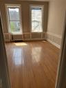 Unfurnished room featuring a decorative wall, light wood-type flooring, radiator heating unit, plenty of natural light, and wainscoting