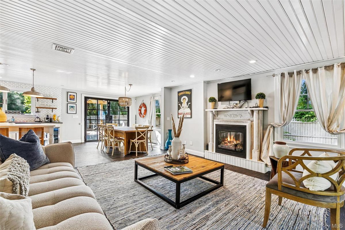 Living area with a glass covered fireplace, wood finished floors, and wooden ceiling