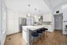 Kitchen with hanging light fixtures, white cabinetry, high quality fridge, a breakfast bar, and a center island with sink