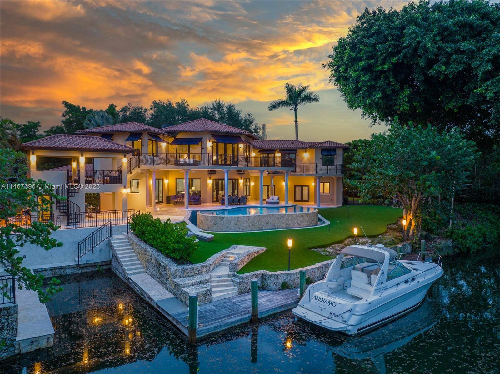 An idyllic waterfront estate, situated on a peaceful double corner lot in the heart of South Coral Gables, set against a picturesque bridge vista, stunning Banyan and mature Oak trees.