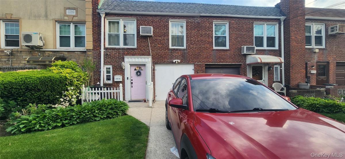 Multi unit property featuring ac unit, a garage, brick siding, and a shingled roof