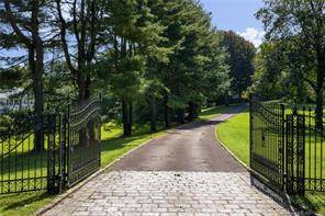 A long gated drive approaches the brick stone English Manor originally built for a 1930's heiress.
