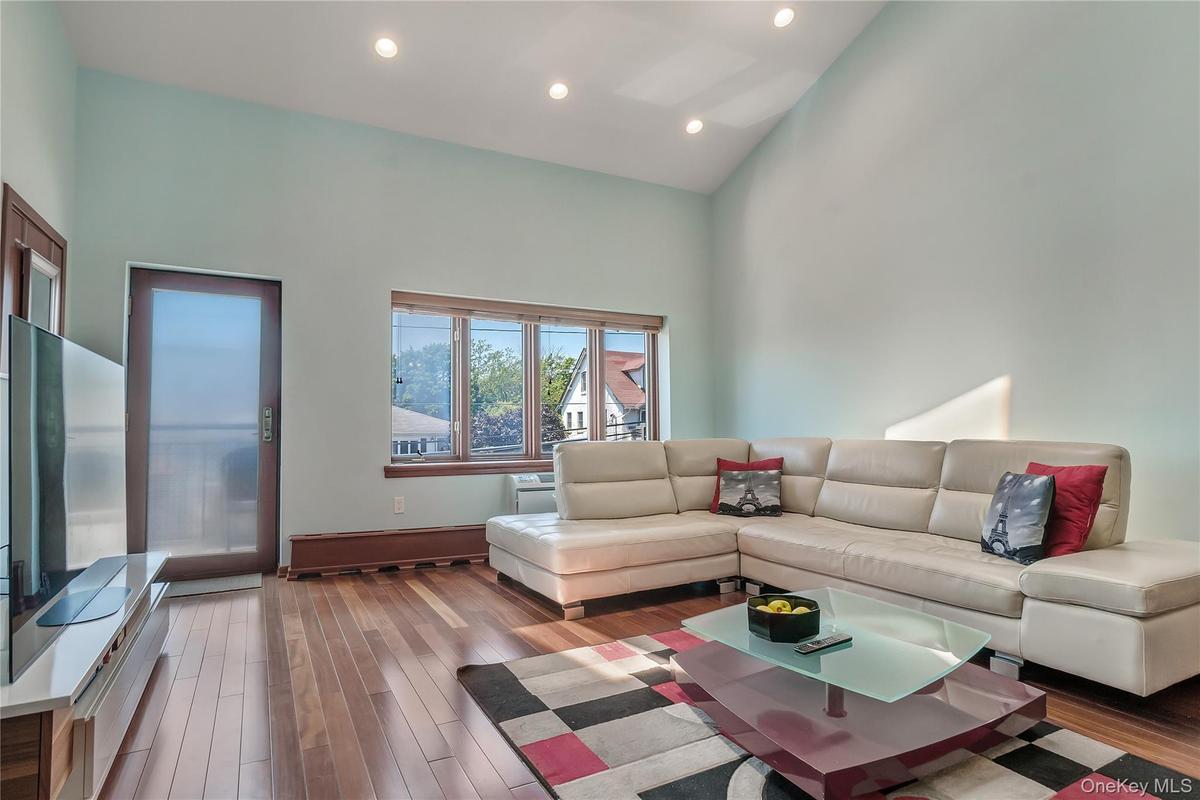 Living area with a towering ceiling, recessed lighting, and hardwood / wood-style flooring