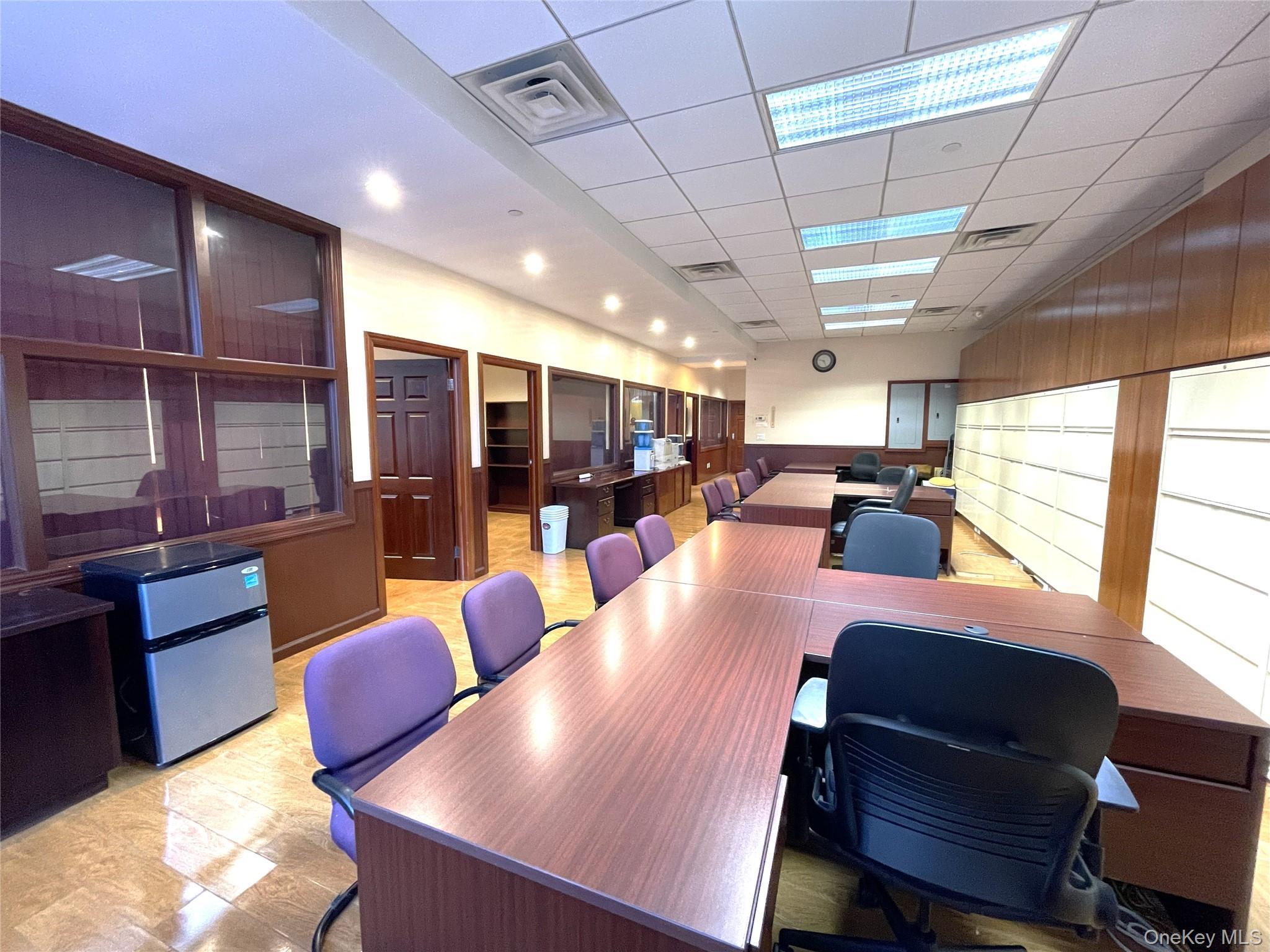 Office space with a drop ceiling, wooden walls, and wainscoting