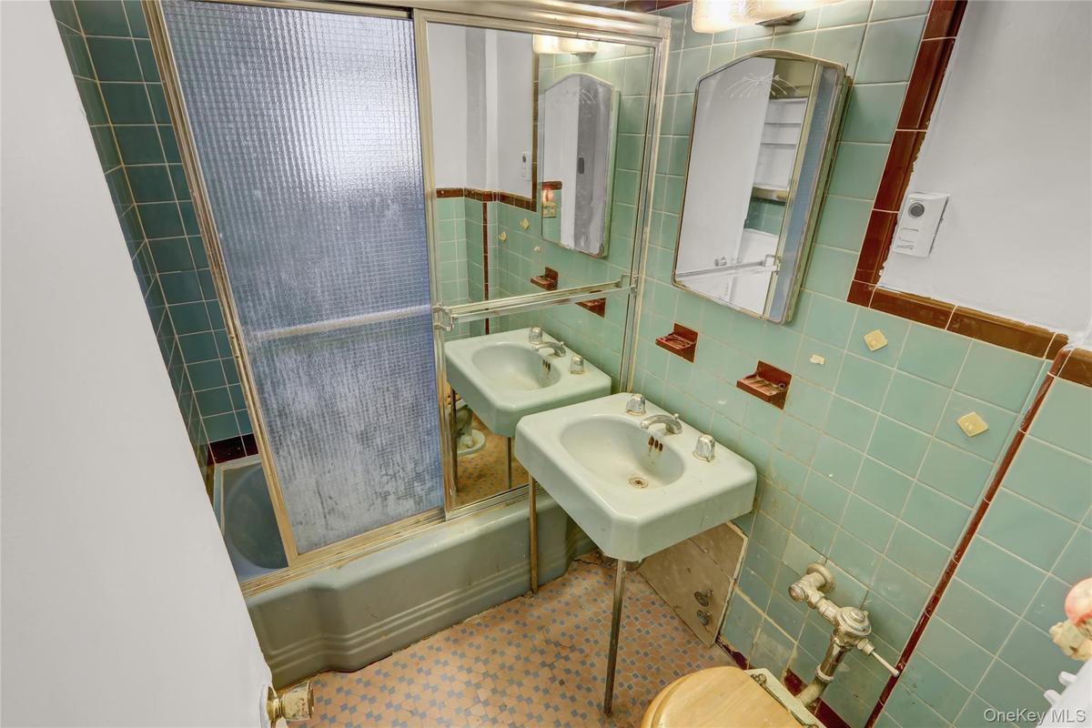 Full bathroom with tile walls and shower / bath combination with glass door