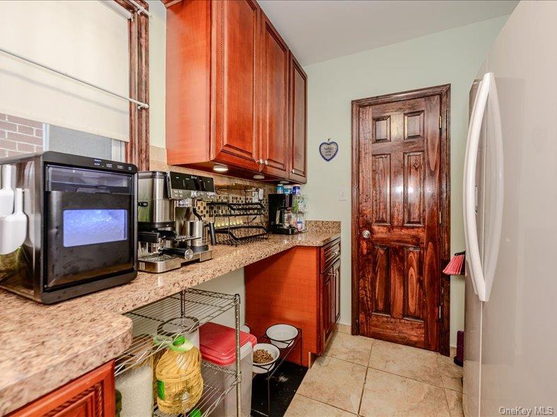 Kitchen area featuring warm-toned cabinetry, and light tile flooring