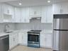 Kitchen featuring appliances with stainless steel finishes, white cabinetry, light stone countertops, extractor fan, and recessed lighting