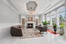 Living area featuring a tray ceiling, a decorative wall, crown molding, a fireplace, and a chandelier