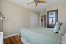 Bedroom 3. Light-filled room featuring wood-finish flooring, a ceiling fan, and white baseboards
