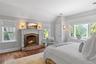 Bedroom with multiple windows, wood finished floors, visible vents, and a brick fireplace