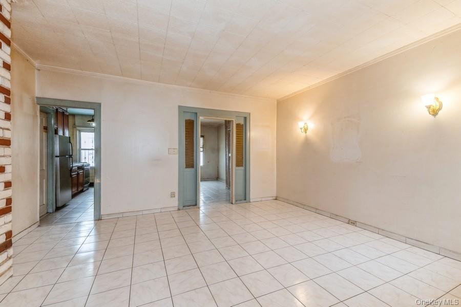 Empty room featuring ornamental molding and light tile patterned flooring