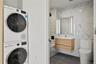 Laundry room featuring tile walls, estacked washer and dryer, and dark tile patterned floors